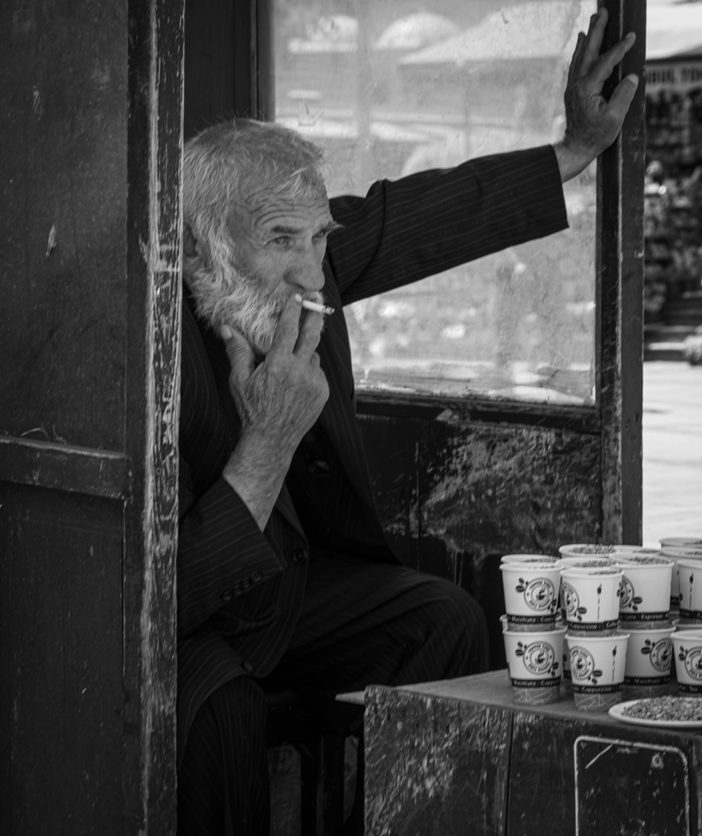 Istanbul Merchant, David Kalb Photography A man sitting in an enclosure smoking a cigarette